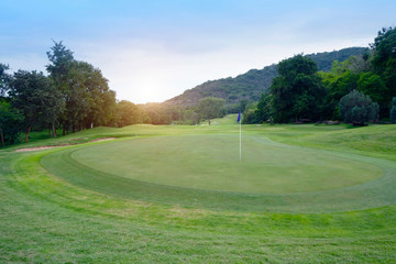 The evening golf course has sunlight shining down at golf course in Thailand