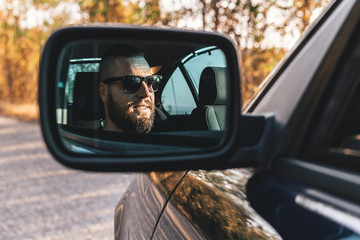 Cute, bearded guy driving a car, reflection in car rearview mirror.