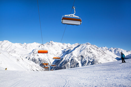 Ski lifts in the Alp mountains, Tirol, Austria. Bright blue sky and mountain covered with snow. 
