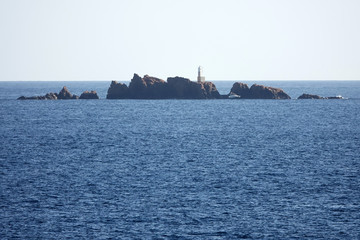Fototapeta premium Island in the sea with a lighthouse and a ship..