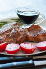Fragrant, juicy meat steaks of veal, beef or pork with rosemary, tomatoes and sauce, on gray plate, on a dark concrete background, vertical format