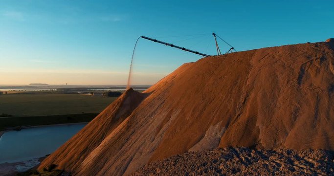 Mountains tailing piles and water basins. Waste left after potash salt ore extraction from underground mines falling from the conveyor belt. Environmental pollution from industrial production.