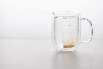 glass thermo mug of water-soluble effervescent orange tablet on a white background