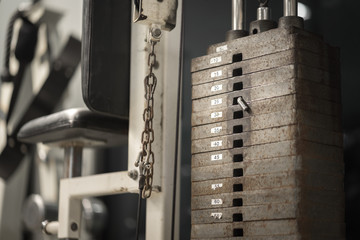 Weight training machine in fitness gym, selective focus at the plate's hole and locking slug.
