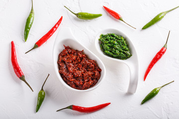 Hot chili pepper paste. Red and green sauce on white background. Adjika or ajika in Georgian cuisine or harissa in Arabic cuisine. Top view.