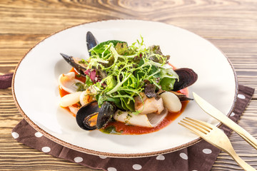 Tasty seafood with green salad mix on white plate on wooden table