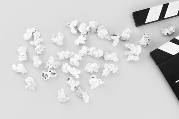 Popcorn and clapperboard on not colorful background
