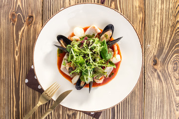 Tasty seafood with green salad mix on white plate on wooden table