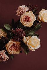 Bouquet of roses, carnations and a protea against dark background