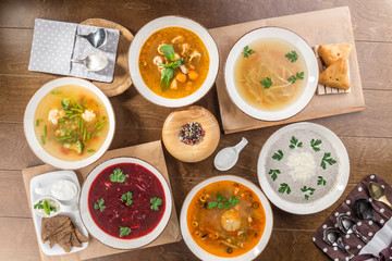 Set of six bowls with different soups combo menu on wooden table