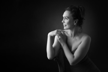 Obraz premium Portrait of a sensual fifty year old woman on grey studio background. Monochrome shot.