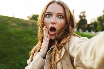 Surprised pretty young ginger woman take selfie by camera.
