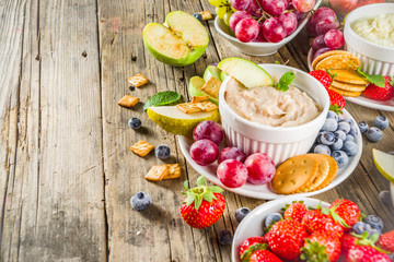 Vegan food for breakfast, snack. Homemade Sweet Hummus with strawberries, apple, crackers, grapes. Variations of different hummus dessert dips - vanilla, chocolate, caramel.