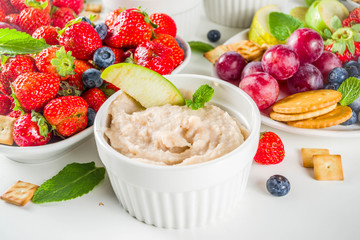 Vegan food for breakfast, snack. Homemade Sweet Hummus with strawberries, apple, crackers, grapes. Variations of different hummus dessert dips - vanilla, chocolate, caramel.
