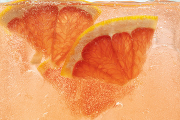 Close up view of the lemon and grapefruit slices in lemonade background. Texture of cooling sweet...
