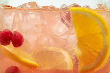 Close up of lemon slices and cherry in lemonade and ice cubes background. Texture of cooling sweet...