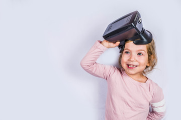 Happy little girl with virtual reality headset glasses. Innovation and VR technology, kids education concept. On white background copy space
