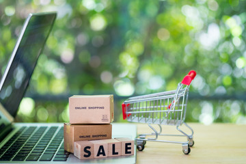 Miniature shopping cart and cardboard boxes on laptop computer