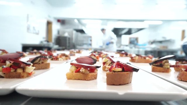 Slow right dolly shot, showing delicious spanish tapas on the plate, with background view in the kitchen. Close up.