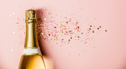 Flat lay of Celebration. Champagne bottle with sprinkles on pink background. © Natalia Klenova