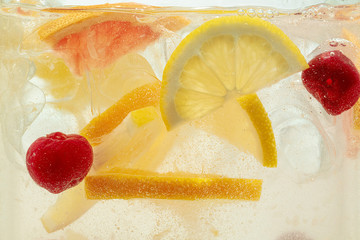 Close up of lemon slices and cherry in lemonade and ice cubes background. Texture of cooling sweet...