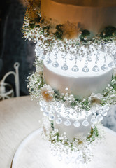 three-level wedding cake on a decorative stand with hanging levels