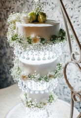 three-level wedding cake on a decorative stand with hanging levels