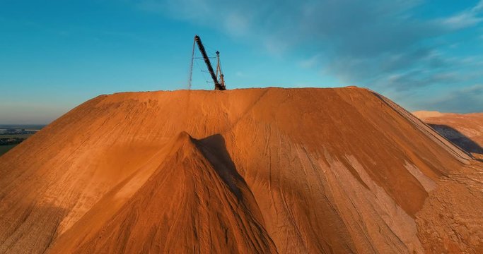 Mountains tailing piles and water basins. Waste left after potash salt ore extraction from underground mines falling from the conveyor belt. Environmental pollution from industrial production.