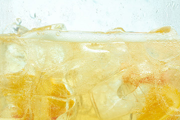 Fototapeta Close up of lemon slices in stirring the lemonade and ice cubes on background. Texture of cooling sweet summer's drink with macro bubbles on the glass wall. Fizzing or floating up to top of surface. obraz