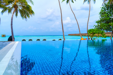 Fototapeta na wymiar Private oceanfront pool with submerged loungers in a luxury reso