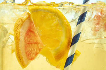 Close up of lemon slices in stirring the lemonade and ice cubes on background. Texture of cooling...