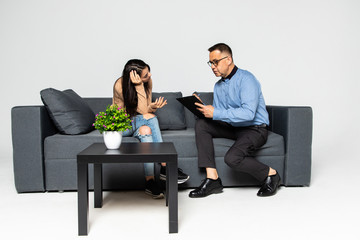Obraz premium Young woman at the mature man psychologist, feeling hopeless and depressed, crying holding her head in hands, upset teenage girl just found out about unwilling pregnancy or having disease