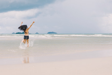 young woman walking and enjoying with water sea on the beach