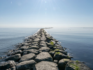 landscape with stone pier in the sea, horizon line in the distance