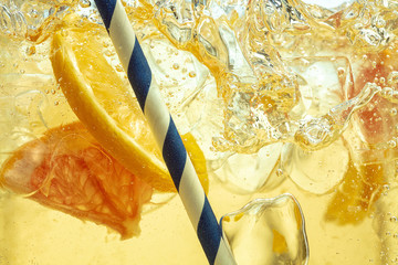 Close up of lemon slices in stirring the lemonade and ice cubes on background. Texture of cooling...