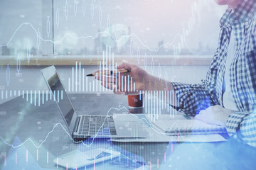 Double exposure of stock market chart with man working on computer on background. Concept of financial analysis.