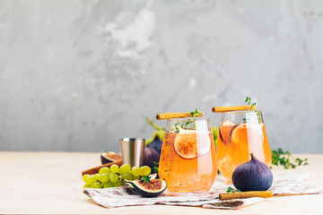 Autumn pink cocktail with fig, thyme, cinnamon and grapes in glass on pink concrete background, close up,