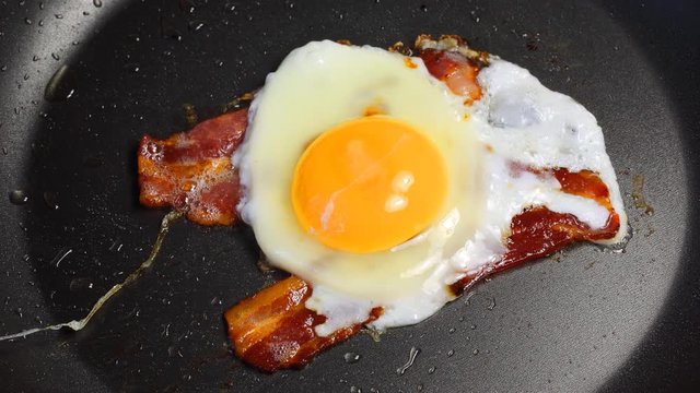 Process of roasting a fried egg (omelette) with bacon in a frying pan, 4K VideoTimelapse