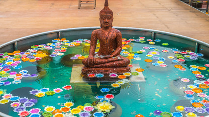 Sitting Buddha in a pond with flowers