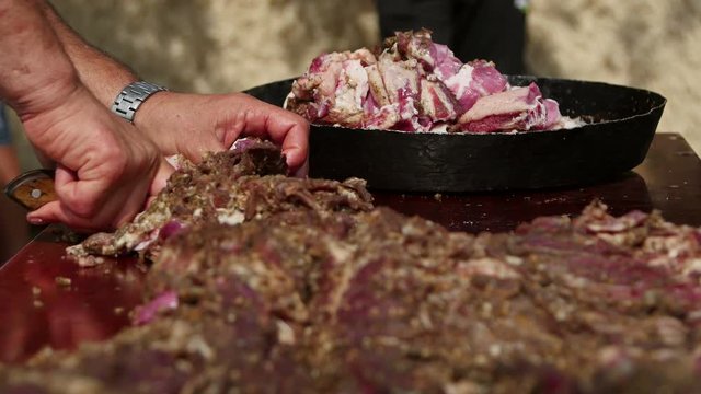 Farmer cutting (pastirma) air-dried spiced lamb meat into small pieces 