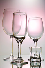 Glasses for different types of alcohol and different capacities on a pink background.