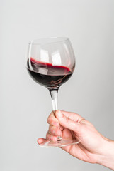 Glass of red wine stirred by adult hand