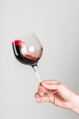 Glass of red wine stirred by adult hand