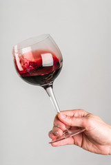 Glass of red wine stirred by adult hand