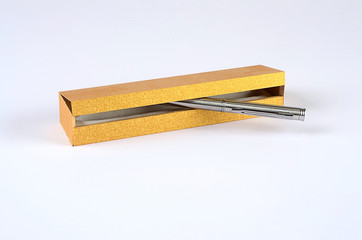 Steel ball pen in golden wooden box on white ground