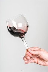 Glass of red wine stirred by adult hand