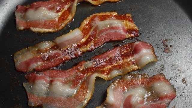 Process of frying thin slices of bacon in a pan, 4K VideoTimelapse