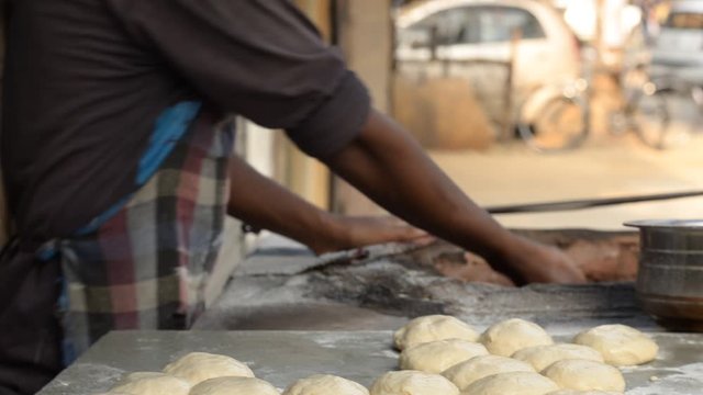 A man putting handmade chapati/ roti/naan bread in Tandoor, a cylindrical clay or metal oven used in cooking and baking in Northern India. It's used for cooking in Southern, Central and Western Asia