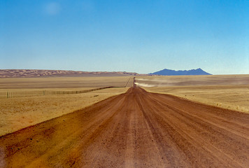 Fototapeta na wymiar Dust clouds left by cars on a namib desert track.