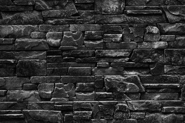 Decorative stone wall with a beautiful hewn stone in dark colors